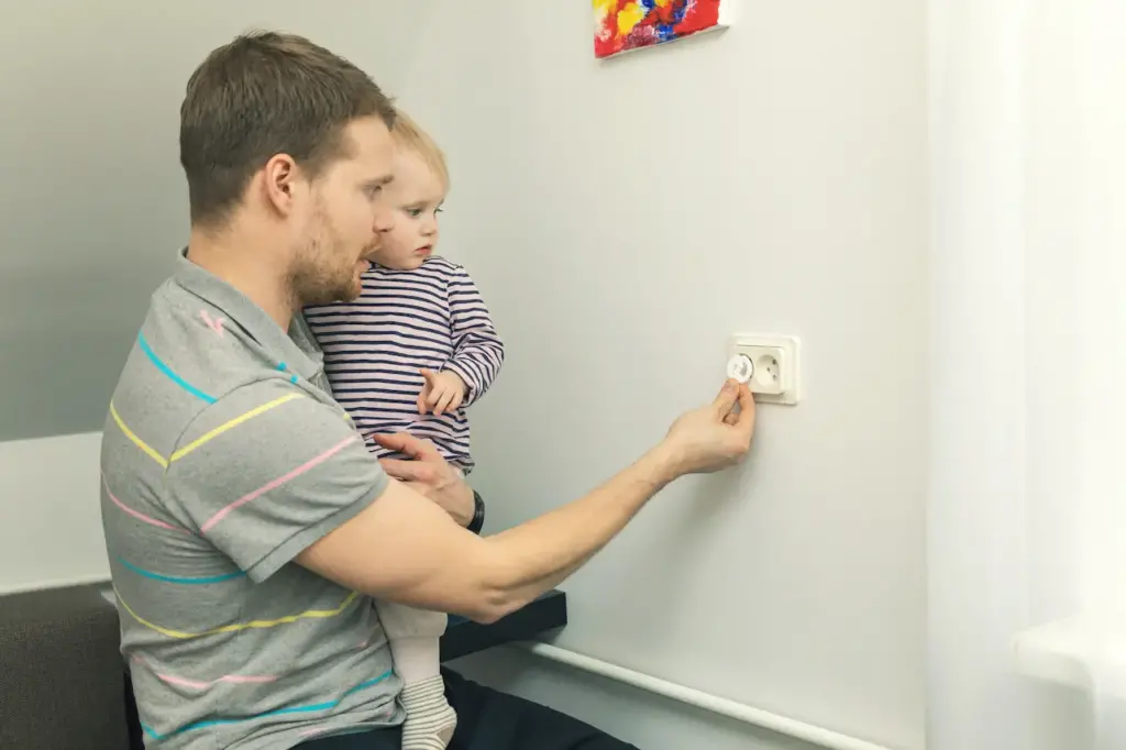 Install Power Points, Father And His Baby Putting Safety Plugs On The Outlet